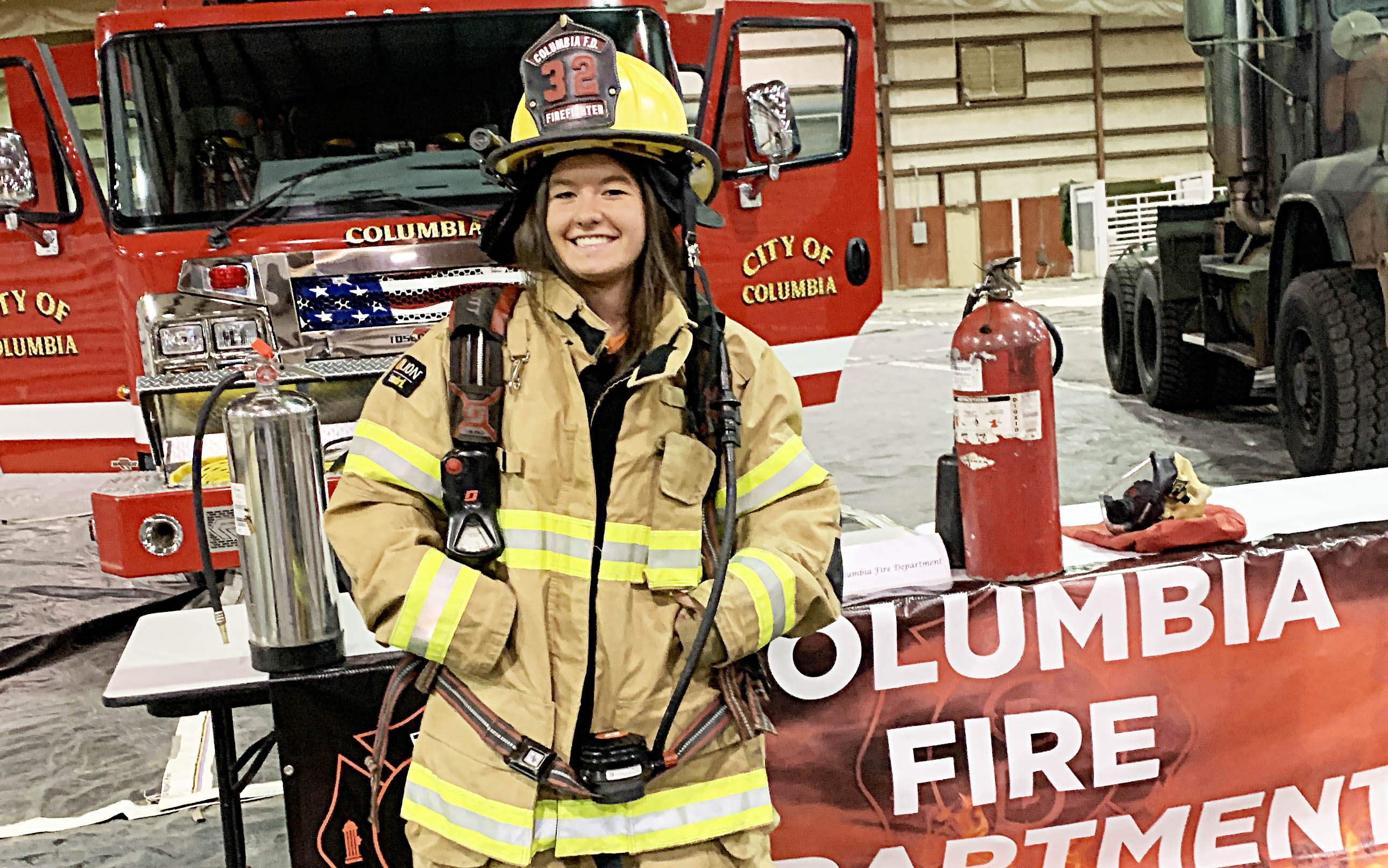 Columbia Fire Chief Lyle Berard shows Anna Price Mattox of Columbia Academy how to put on the gear used by Firefighters.