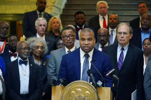 Hinds County District Attorney Jody Owens, center, stands with Lt. Gov. Delbert Hosemann, right, and a delegation of Hinds County legislators, supervisors, lawmen, and U.S. Rep. Michael Guest, R-Miss., and speaks to reporters about the Hinds County Public Safety Initiative, a project they believe will address crime in Hinds County through temporary judges, assistant district attorneys, and public defenders, Wednesday, May 4, 2022, in Jackson, Miss. (AP Photo/Rogelio V. Solis)