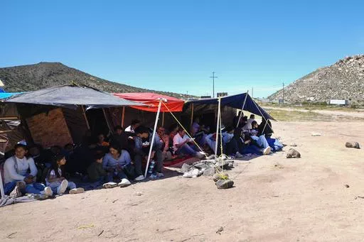 A group of people wait to be processed after crossing the border between Mexico and the United States as they seek asylum, Wednesday, April 17, 2024, near Jacumba, Calif. (AP Photo/Gregory Bull)