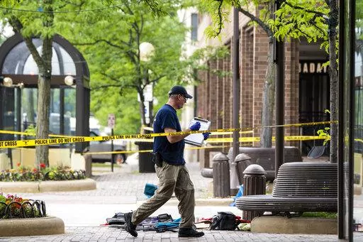 Members of the FBI's Evidence Response Team Unit investigate on Central Avenue near Green Bay Road in downtown Highland Park, Ill., less than 24 hours after a gunman killed several people and wounded dozens more by firing a high-powered rifle from a rooftop onto a crowd attending Highland Park's Fourth of July parade, Tuesday morning, July 5, 2022. (Ashlee Rezin/Chicago Sun-Times via AP)