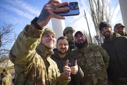 In this photo provided by the Ukrainian Presidential Press Office and posted on Facebook, Ukrainian soldiers take a selfie with President Volodymyr Zelenskyy, centre, during his visit to Kherson, Ukraine, Monday, Nov. 14, 2022. Ukraine's retaking of Kherson was a significant setback for the Kremlin and it came some six weeks after Russian President Vladimir Putin annexed the Kherson region and three other provinces in southern and eastern Ukraine — in breach of international law — and declar
