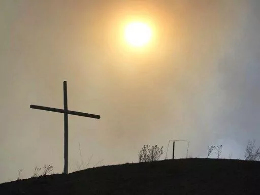 This May 4, 2022 image courtesy of Laura Paskus shows the silhouette of a cross amid smokey skies where hundreds of firefighters are battling a massive wildfire burning in the Sangre de Cristo Mountains near the community of Las Vegas, New Mexico. (Laura Paskus via AP)