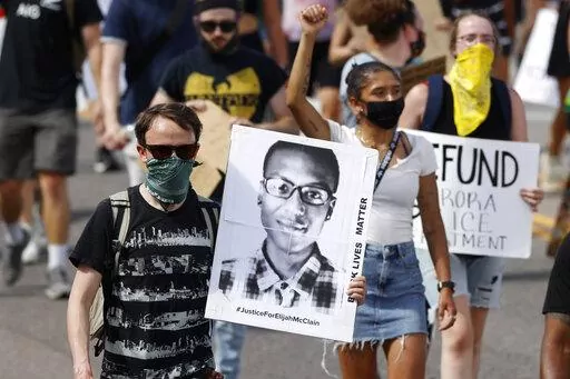 A demonstrator carries an image of Elijah McClain during a rally and march in Aurora, Colo., June 27, 2020. A Colorado judge on Friday, Sept. 16, 2022 responded to a request by a coalition of news organizations to release an amended autopsy report for Elijah McClain, a 23-year-old Black man who died after a 2019 encounter with police, by ruling the report be made public only after new information it contains is redacted. (AP Photo/David Zalubowski, File)