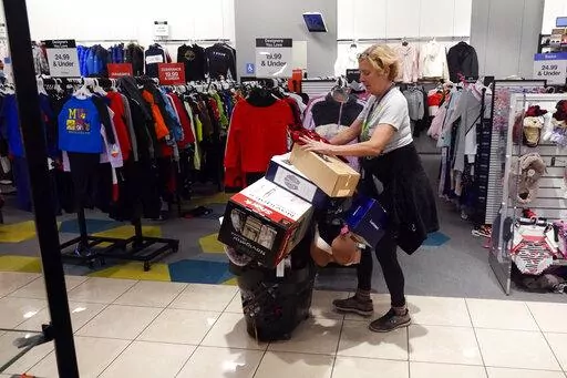 FILE - A shopper pushes her cart full of items down an isle during a Black Friday sale at Macy's, Friday, Nov. 26, 2021, in Indianapolis.  Holiday sales rose at the fastest pace in 17 years, even as shoppers grappled with higher prices, product shortages and a raging new COVID-19 variant in the last few weeks of the season,  according to one spending measure. (AP Photo/Darron Cummings, File)