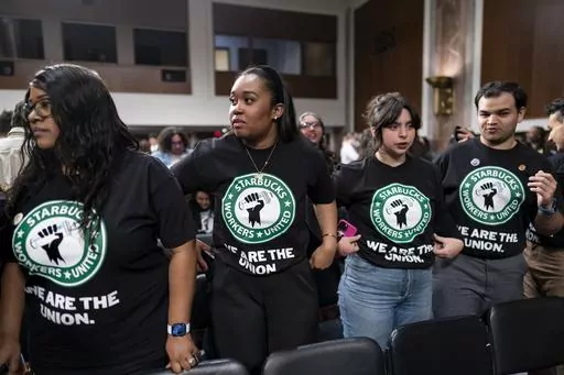 Advocates for a union for Starbucks employees watch as company founder Howard Schultz leaves a hearing after testifying to the Senate Health, Education, Labor and Pensions Committee at the Capitol in Washington on March 29, 2023. Starbucks says it’s committed to bargaining with unionized workers and reaching labor agreements next year. The move Friday is major reversal for the coffee chain after two years fighting the unionization of its U.S. stores. (AP Photo/J. Scott Applewhite, File)