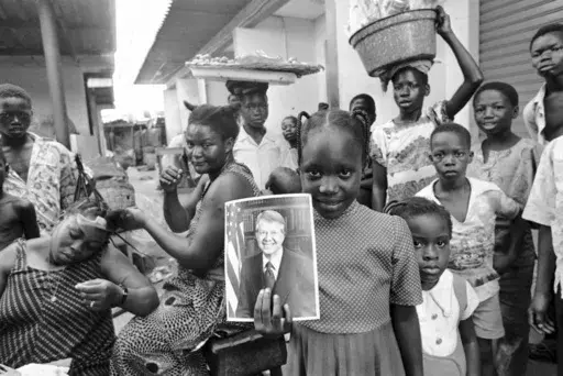 A girl holds a portrait of U.S. President Jimmy Carter in a market in Lagos, Nigeria, March 31, 1978, the day of his arrival for a state visit, the first to Africa by an American president. (AP Photo/Dieter Endlicher, File)