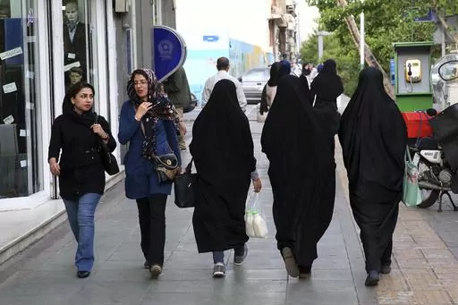 Iranian women make their way along a sidewalk in downtown Tehran, Iran, Tuesday, April 26, 2016. Iranian police have announced a new campaign to force women to wear the Islamic headscarf. Morality police returned to the streets on Sunday, 10 months after the death of a woman in their custody sparked nationwide protests. (AP Photo/Vahid Salemi, File)