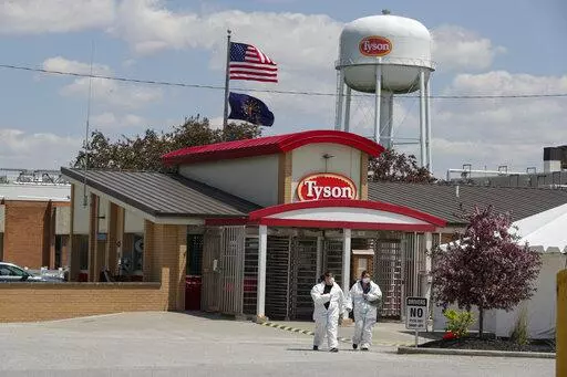 In this May 7, 2020 file photo, workers leave the Tyson Foods pork processing plant in Logansport, Ind.  At the height of the pandemic, the meat processing industry worked closely with political appointees in the Trump administration to stave off health restrictions and keep processing plants open even as COVID-19 spread rapidly among workers, according to a new Congressional report released Thursday, May 12, 2022. (AP Photo/Michael Conroy, File)