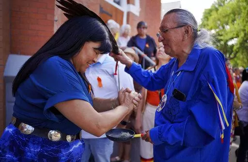 Marlene Poitras participates in a smudging, a ceremonial burning of scented plants for purification and blessing, with church elder Fernie Marty outside of Sacred Heart Church of the First Peoples on Sunday, July 17, 2022, in Edmonton, Alberta. Marty is a survivor of a day school for Indigenous children, which had culturally repressive policies similar to that of residential schools. He has continued practicing his Catholic faith in conjunction with Indigenous ceremonies. (AP Photo/Jessie Wardar