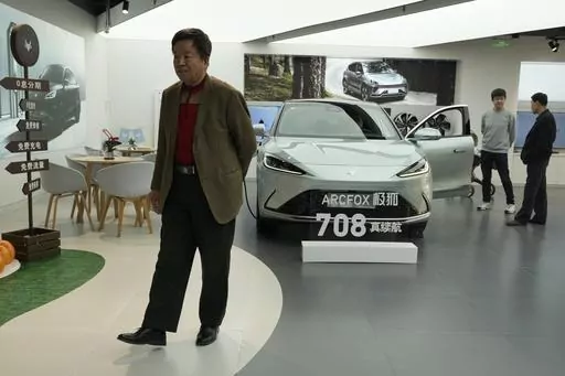 Visitors look at the Arcfox a-S, an all electric car from Chinese automaker BAIC which claims to have a 708km range on a single charge, at a show room in Beijing, Thursday, April 13, 2023. Global and Chinese automakers plan to unveil more than a dozen new electric SUVs, sedans and muscle cars this week at the Shanghai auto show, their first full-scale sales event in four years in a market that has become a workshop for developing electrics, self-driving cars and other technology. (AP Photo/Ng Ha