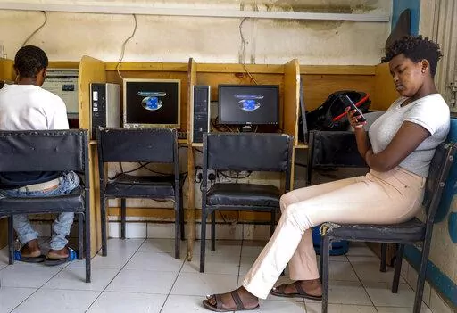 A customer uses the Wi-Fi on her mobile phone at an internet cafe in the low-income Kibera neighborhood of Nairobi, Kenya on Sept. 29, 2021. Facebook has failed to catch Islamic State group and al-Shabab extremist content in posts aimed at East Africa as the region remains under threat from violent attacks and Kenya prepares to vote in a closely contested national election, according to a new study released Wednesday, June 15, 2022. (AP Photo/Brian Inganga, File)