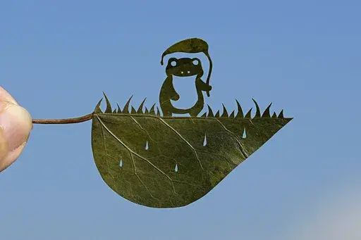 Japanese leaf-cutting artist, who goes by the name Lito, holds his freshly cut work featuring a frog with an umbrella, during an interview in Tokyo Wednesday, Nov. 27, 2024. (AP Photo/Shuji Kajiyama)