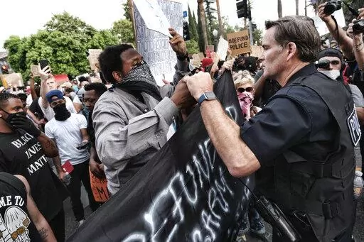 Los Angeles Captain Cory Palka, right reaches out and offers a handshake to a "Black Lives Matter" protester outside Los Angeles Mayor Garcetti's house in Los Angeles Tuesday, June 2, 2020. CBS and its former president, Leslie Moonves, will pay $30.5 million as part of an agreement with the New York attorney general's office, which says the network's executives conspired with a Los Angeles police captain later identified as Palka to conceal sexual assault allegations against Moonves. (AP Photo/R