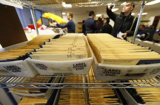 In this Oct. 31, 2018, file photo, early ballots wait in bins to be sorted in the Denver Elections Division headquarters in Denver. On Friday, Oct. 28, 2022, The Associated Press reported on stories circulating online incorrectly claiming Colorado’s practice of sending mail-in ballots to every registered voter is unconstitutional. and voters should only vote in person on Election Day. (AP Photo/David Zalubowski, File)