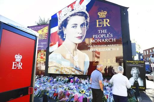 A couple pay their respect at a picture of Queen Elizabeth II on the Loyalist Shankill Road in west Belfast, Sept. 10, 2022. Britain's longest-reigning monarch and a rock of stability across much of a turbulent century, died Sept. 8, 2022. (AP Photo/Peter Morrison, File)