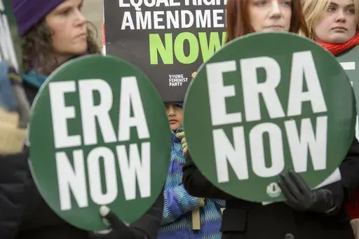 A girl is seen in between "ERA NOW" signs as people hold a rally in front of the National Archives to highlight President Joe Biden's decision to declare the Equal Rights Amendment (ERA) as the 28th Amendment to the United States Constitution, Friday, Jan. 17, 2025, in Washington. (AP Photo/Rod Lamkey, Jr.)