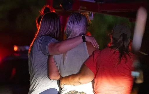 Family and friends embrace each other as Indianapolis Metropolitan Police Department investigators search for a father and three children Tuesday, July 12, 2022, on Bluff Road in Indianapolis. The bodies of a man and three young children were found in an Indianapolis pond amid a search for a father and his kids who had been missing since last week, authorities said Wednesday. (Grace Hollars/The Indianapolis Star via AP)