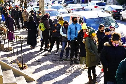 City residents wait in a line extending around the block to receive free at-home rapid COVID-19 test kits in Philadelphia, Monday, Dec. 20, 2021. (AP Photo/Matt Rourke)