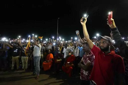 Sri Lankans hold up their mobile phone torches during a vigil condemning police shooting at protesters in Rambukkana, 90 kilometers (55 miles) northeast of Colombo, at a protest outside the president's office in Colombo, Sri Lanka, Tuesday, April 19, 2022. Sri Lankan police opened fire Tuesday at a group of people protesting new fuel price increases, killing one and injuring 10 others, in the first shooting by security forces during weeks of demonstrations over the country's worst economic crisi