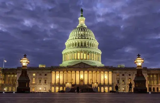 Lights shine inside the U.S. Capitol Building as night falls on Jan. 21, 2018, in Washington. (AP Photo/J. David Ake, File)