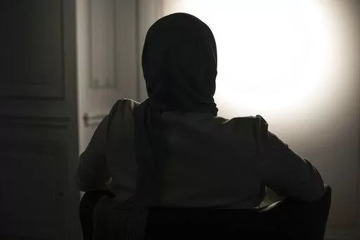 The sister, who refused to show and identify, of a woman imprisoned in Turkey is silhouetted during an interview with The Associated Press in Paris, Wednesday, Feb. 16, 2022. Shatz and a team of European lawyers filed a case against Greece at the European Court of Human Rights on behalf of a 32-year-old French woman who accuses the Hellenic country of forcibly pushing her back across the border from Greece to Turkey, where she claims she is a victim of political persecution. The woman, who is al