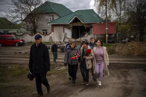 Tetiana Boikiv, 52, center, walks with friends and neighbors during a funeral service for her husband, Mykola "Kolia" Moroz, 47, in the Ukrainian village of Ozera, near Bucha, on Tuesday, April 26, 2022. Russian soldiers took Kolia from his house on March 15. He was tortured and shot, his body found two weeks later in a village 15 kilometers (9 miles) away where Russians set up a major forward operating base for their assault on the capitol, Kyiv. (AP Photo/Emilio Morenatti)