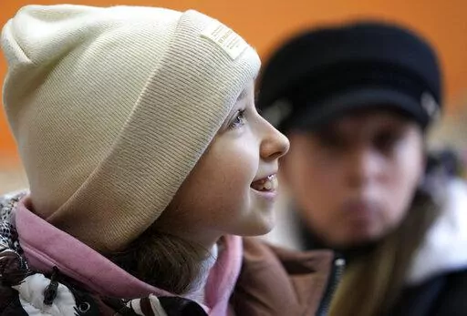 Annamaria Moslovska, a ten-year-old from Kharkiv, eastern Ukraine, smiles in a waiting room at the train station in Zahony, Hungary, Monday, March 7, 2022. After hearing bombs falling in her hometown of Kharkiv, Annamaria Maslovska left her friends, her toys, and her life in Ukraine and set off on a two-day journey with her mother to Hungary. From inside the train station at the town of Zahony, on Hungary's border with Ukraine, the 10-year-old said she is worried about her friends in Kharkiv aft
