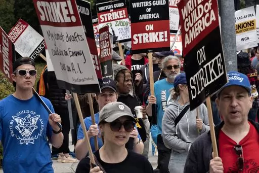 FILE -Picketers pass near a studio entrance during a Writers Guild rally outside Warner Bros. Studios, Wednesday, May 24, 2023, in Burbank, Calif. As a strike drags on, about 1,000 Hollywood writers and their supporters have marched and rallied in Los Angeles for a new contract with studios that includes the payment guarantees and job security they say they deserve. Speakers at Wednesday's event on June 21, emphasized the solidarity the Writers Guild of America has received from other unions. (A