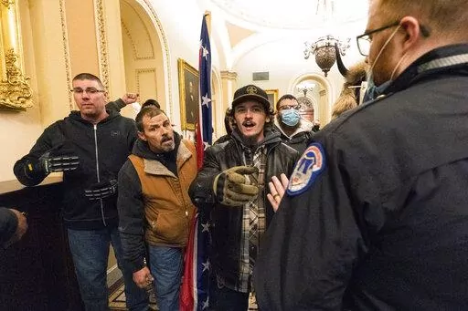 Kevin Seefried, second from left, holds a Confederate battle flag as he and other insurrectionists loyal to President Donald Trump are confronted by U.S. Capitol Police officers outside the Senate Chamber inside the Capitol in Washington, Jan. 6, 2021. A federal judge on Wednesday, June 15, 2022, convicted Kevin Seefried and his adult son Hunter Seefried of charges that they stormed the U.S. Capitol together to obstruct Congress from certifying President Joe Biden’s 2020 electoral victory. (A