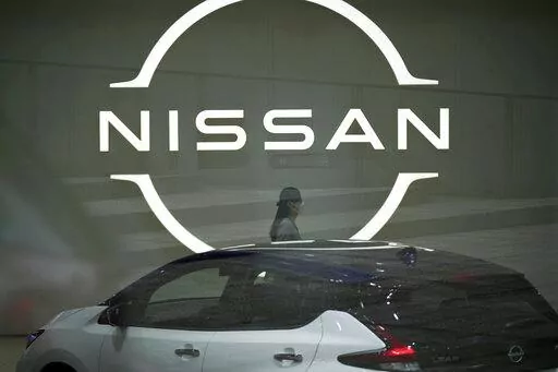A staff walking near a Nissan logo at Nissan headquarters is seen though a window on May 12, 2022, in Yokohama near Tokyo. Nissan and Renault have changed their mutual cross-shareholdings to the same 15%, ironing out a source of conflict in the Japan-French auto alliance. (AP Photo/Eugene Hoshiko, File)