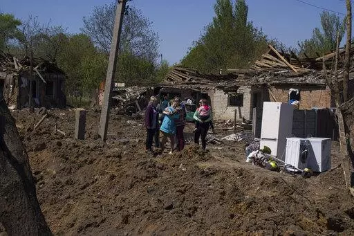 People react as they stand next to a crater in destroyed residential area after Russian airstrike in Bakhmut, Donetsk region, Ukraine, Saturday, May 7, 2022. (AP Photo/Evgeniy Maloletka)