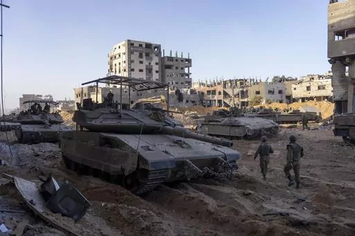 Israeli army troops are seen next to a destroyed building during a ground operation in the Gaza Strip on Nov. 8, 2023. As the military sets its sights on southern Gaza in its campaign to stamp out Hamas, key challenges loom. International patience for a protracted invasion has begun to wear thin. And with some 2 million displaced Gaza residents staying in crowded shelters in the south in dire conditions, a broad military offensive there could unleash a new humanitarian disaster during the cold, 