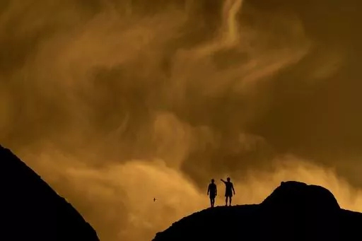 People watch the sunset from a peak at Papago Park, Feb. 19, 2021, in Phoenix. (AP Photo/Charlie Riedel, File)