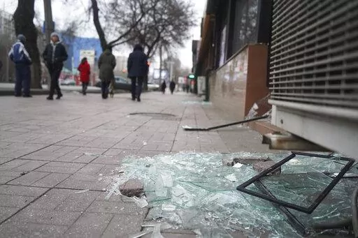 People walk past a shop with windows broken during clashes in Almaty, Kazakhstan, Monday, Jan. 10, 2022. Kazakhstan's health ministry says over 150 people have been killed in protests that have rocked the country over the past week. President Kassym-Jomart Tokayev's office said Sunday that order has stabilized in the country and that authorities have regained control of administrative buildings that were occupied by protesters, some of which were set on fire. (Vladimir Tretyakov/NUR.KZ via AP)