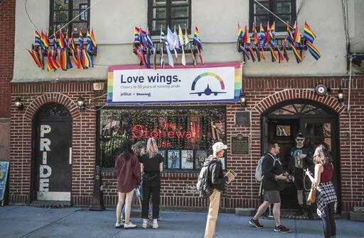 In this Monday, June 3, 2019, file photo, Pride flags and colors display on the Stonewall Inn bar, marking the site of 1969 riots that followed a police raid of the bar's gay patrons, in New York. A visitor center dedicated to telling the story of LGBTQ rights movement will open next door to the Stonewall Inn. Organizers say the groundbreaking for the Stonewall National Monument Visitor Center in New York City's Greenwich Village neighborhood will take place Friday, June 24, 2022. (AP Photo/Bebe