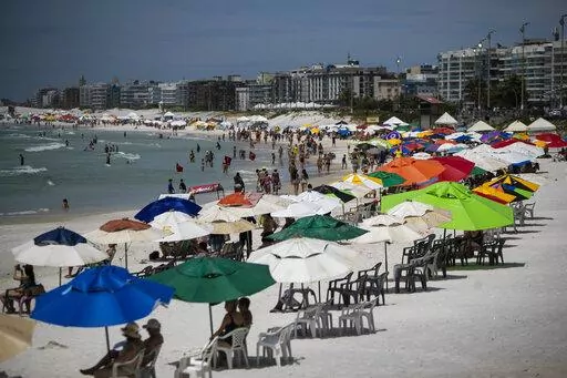 Beachgoers congregate on Fort Beach in Cabo Frio, Brazil, Wednesday, Dec. 15, 2021. G.A.S Consulting & Technology, a cryptocurrency investment firm founded by Glaidson Acacio dos Santos, a former waiter-turned-multimillionaire who is the central figure in what is alleged to be one of Brazil’s biggest-ever pyramid schemes, was based in the beach town dos Santos called home. (AP Photo/Bruna Prado)