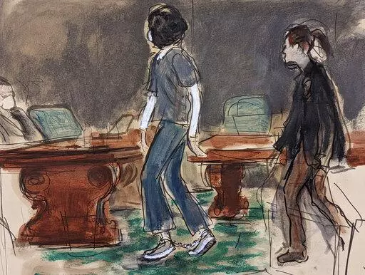 In this courtroom sketch, Ghislaine Maxwell, left, escorted by a U.S. Marshal, wears leg shackles as she enters the courtroom for her sentencing in federal court, Tuesday, June 28, 2022, in New York. Maxwell was sentenced on Tuesday to 20 years in prison for helping the wealthy financier Jeffrey Epstein sexually abuse teenage girls. (AP Photo/Elizabeth Williams)