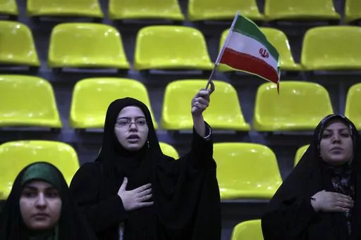Iranian women listen to their country's national anthem as one of them waves the national flag during an election campaign rally ahead of the March 1, parliamentary and Assembly of Experts elections, in Tehran, Iran, Tuesday, Feb. 27, 2024. Iran is holding parliamentary elections this Friday, yet the real question may not be who gets elected but how many people actually turn out to vote. Separately, Iranians will also vote on Friday for members of the country's 88-seat Assembly of Experts, an ei
