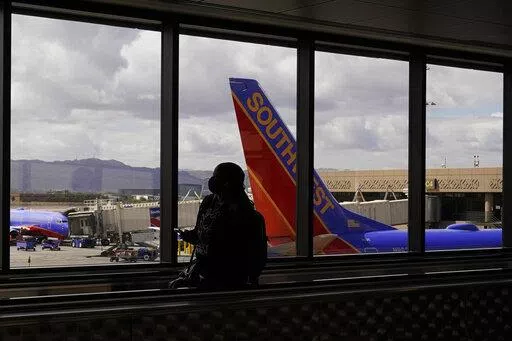 A passenger walks past a Southwest Airlines plane at Sky Harbor International Airport in Phoenix, March 26, 2021. AT&T and Verizon have agreed to delay the launch of a new slice of 5G service by two weeks after airlines and the nation's aviation regulator complained about potential interference with systems on board planes. (AP Photo/Sue Ogrocki, File)