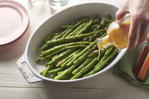 A vinaigrette dressing is poured over grilled asparagus in February 2020. Beyond lettuce salads, think about other uses for your vinaigrette. Drizzle some on simply cooked vegetables like grilled asparagus, or use it in a mayo-free potato salad. (Cheyenne M. Cohen via AP)