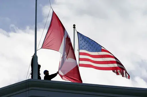 Washington State Park workers put up a new Canadian flag in front of an American flag about to be replaced during scheduled maintenance atop the Peace Arch in Peace Arch Historical State Park Monday, Nov. 8, 2021, in Blaine, Wash. (AP Photo/Elaine Thompson, File)