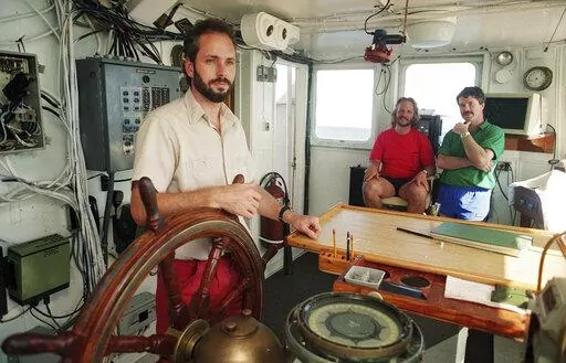 In this Aug. 29, 1991, file photo, Tommy Thompson stands at the helm of the Arctic Explorer as Bob Evans, center, and Barry Schatz look on in Norfolk, Va. Thompson, a former deep-sea treasure hunter, is about to mark his fifth year in jail for refusing to disclose the whereabouts of 500 missing gold coins found in the historic shipwreck of the S.S. Central America, known as the Ship of Gold. (Doral Chenoweth III/The Columbus Dispatch via AP, File)
