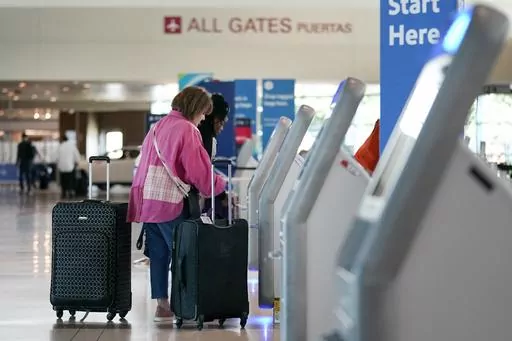 Travelers use the kiosk by the ticketing gate as they prepare for travel from Love Field airport, May 19, 2023, in Dallas. When booking flights, navigating extra fees and upgrades can be overwhelming, which is no accident. Behavioral economics, a field that combines psychology with traditional economics, highlights the many biases that drive us to pay more than we have to. (AP Photo/Tony Gutierrez, File)