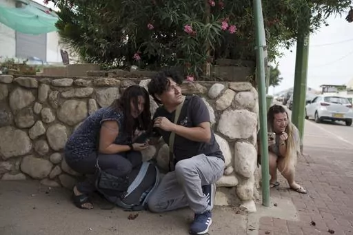 Israelis take cover from the incoming rocket fire from the Gaza Strip in Ashkelon, southern Israel on Oct. 11, 2023. (AP Photo/Leo Correa, File)