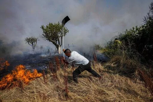 A local resident fights a forest fire with a shovel during a wildfire in Tabara, north-west Spain, July 19, 2022. Major wildfires in Europe are starting earlier in the year, becoming more frequent, doing more damage and getting harder to stop. And, scientists say, they’re probably going to get worse as climate change intensifies unless countermeasures are taken.  (AP Photo/Bernat Armangue, File)