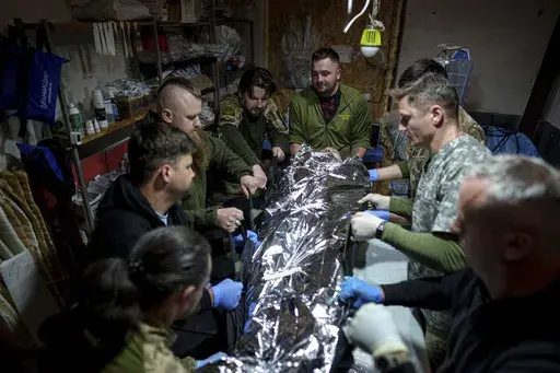 Ukrainian military medics of the 47th Brigade shift an injured comrade to a stretcher at the field hospital in Avdiivka direction, Donetsk region, Ukraine, Friday, May 10, 2024. (AP Photo/Evgeniy Maloletka)