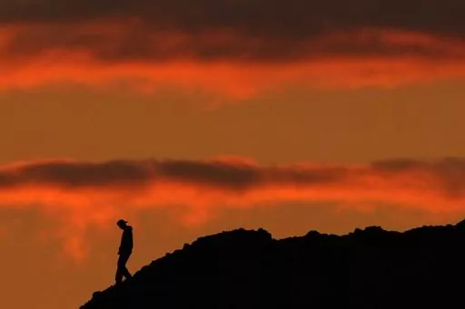 A person is silhouetted against the sky at sunset at Papago Park in Phoenix on Thursday, March 2, 2023. The homicide rate for older U.S. teenagers rose to its highest point in nearly 25 years during the COVID-19 pandemic, and the suicide rate for adults in their early 20s was the worst in more than 50 years, government researchers said Thursday, June 15. (AP Photo/Charlie Riedel)