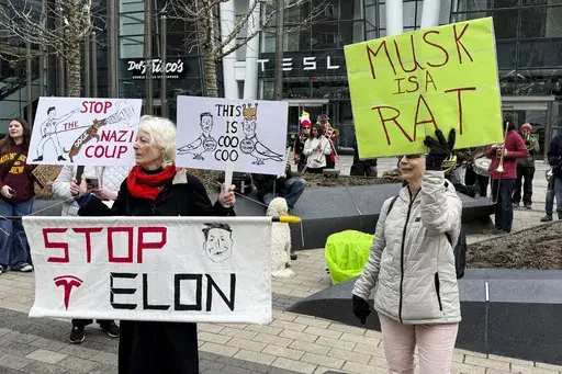 Protesters rally outside of a Tesla store in Boston, Saturday, March 1, 2025, against the company's CEO, Elon Musk, who is leading an effort to cut government jobs on behalf of President Donald Trump. (AP Photo/Rodrique Ngowi)