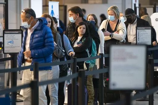 Passengers wait in line at the security checkpoint at Ronald Reagan Washington National Airport, Tuesday, April 19, 2022, in Arlington, Va. The Justice Department is filing an appeal seeking to overturn a judge’s order that voided the federal mask mandate on planes and trains and in travel hubs. The notice came minutes after the Centers for Disease Control and Prevention asked the Justice Department to appeal the decision handed down by a federal judge in Florida earlier this week. (AP Photo/E