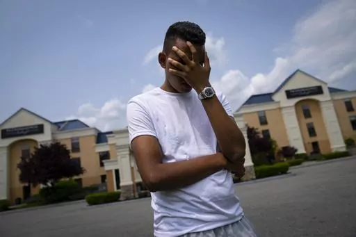 Mohamed, a 19-year-old fleeing political persecution in the northwest African country of Mauritania, poses for a photo that obscures his face to protect his identity, outside the Crossroads Hotel, before heading into town for a work opportunity, Monday, May 22, 2023, in Newburgh, N.Y. Mohamed is one of about 400 international migrants the city has been putting up in a small number of hotels in other parts of the state this month to relieve pressure on its overtaxed homeless shelter system. (AP P